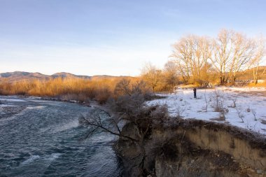 Dağ eteklerinde kış, buzsuz bir nehir, dondurucu bir sabah, yükselen güneşin ışınlarında..