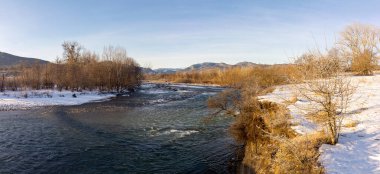 Dağ eteklerinde kış, buzsuz bir nehir, dondurucu bir sabah, yükselen güneşin ışınlarında..
