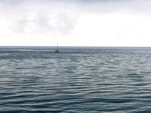 A yacht going on a small sea trip, in cloudy weather and a slight sea disturbance.