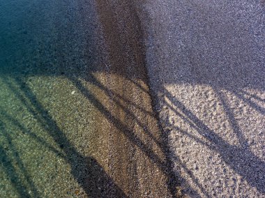 Deniz kıyısı, sakin bir durumda, küçük bir gelgit ve tuhaf desenleri ve gölgeleri olan küçük bir dalga..