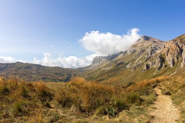 Sıcak, güneşli bir sonbahar gününde dağların dağlık alandaki yürüyüş patikalarından doğayla yürüme ve iletişim kurma panoramik manzarası..