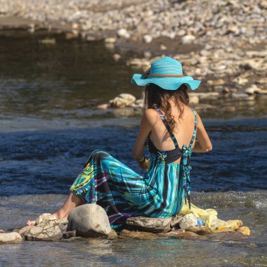 Genç bir fotoğrafçı ve tasarımcı kız nehir kıyısında bir fotoğraf çekimi ve güneşli bir yaz gününde köprü desteği için bir iç mekan geliştiriyor..
