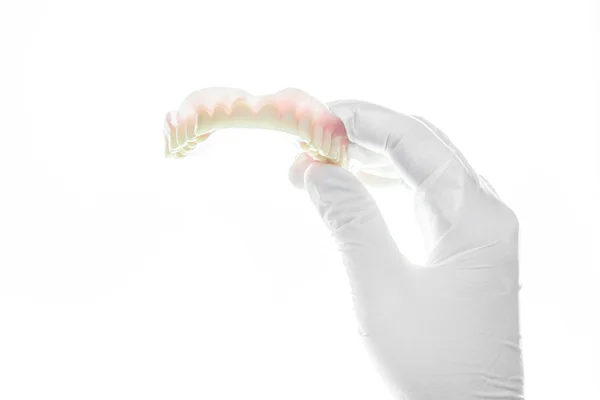 Denture and handglove on white background — Stock Photo, Image