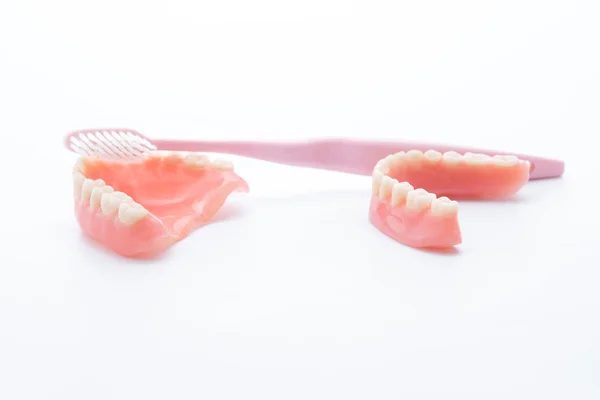 Dentaduras acrílicas com escova de dentes no backgroun branco — Fotografia de Stock