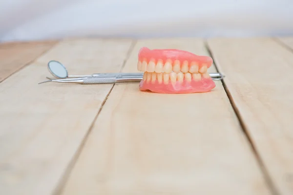 Dentaduras e ferramentas dentárias em mesa de madeira — Fotografia de Stock