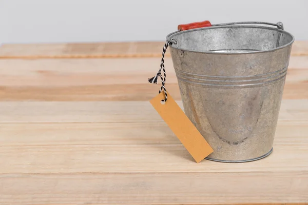 Un cubo de metal vintage sobre fondo de madera con etiqueta —  Fotos de Stock