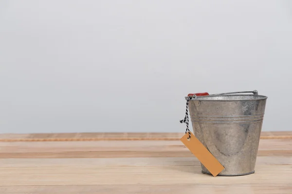 a vintage metal bucket on wooden background with tag