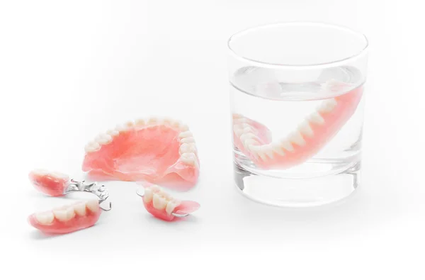 Set de Dentadura en vaso de agua sobre fondo blanco —  Fotos de Stock