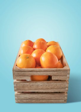 Ahşap bir kutuda taze portakallar, mavi arkaplan whit kopyalama alanından izole