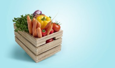 Mavi zemin üzerinde ahşap bir kutuda taze sebzeler ve fotokopi alanı