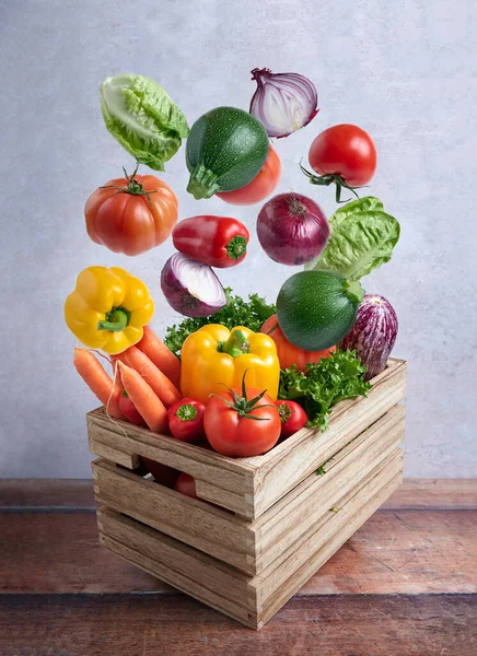 Fresh vegetables flying in a wooden box on rustic background