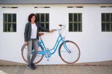 middle-aged woman with bicycle painted on a wall