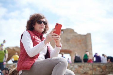 Turistik bir yerde selfie çeken orta yaşlı bir kadın.