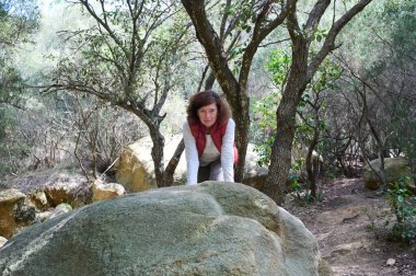 Dağdaki bir taşın üzerinde poz veren yürüyüşçü kadın.