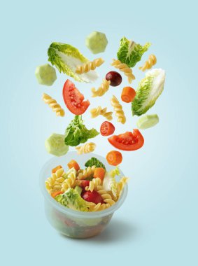 Makarna salatası kabın içine düşüyor. Hızlı ve sağlıklı gıda konsepti