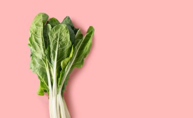 Bunch of chard on pink background with copy space