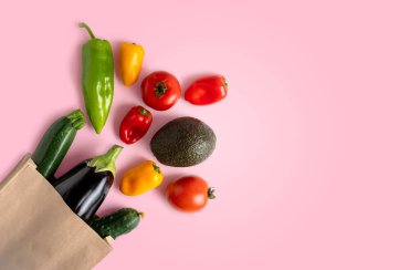 Vegetable in a recyclable paper bag on pink background with copy space