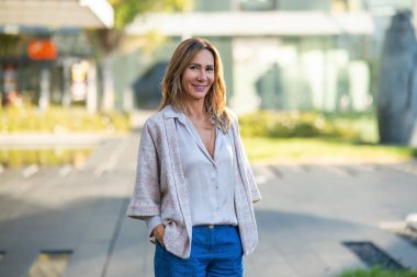 Confident mature businesswoman modeling casual business wear outdoors, looking at camera