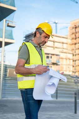 Engineer man reviewing building plans at construction site