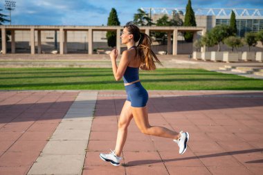 Şehir parkında koşan kadın açık havada antrenman yapıyor.