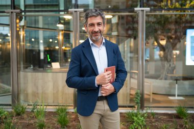 Kendine güveni tam bir işadamı elinde kırmızı bir defter, gülümsüyor