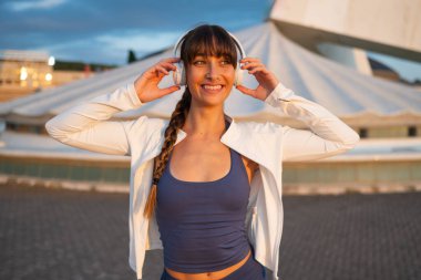 Dışarıda kulaklık takıp müzik dinleyen mutlu bir kadın.