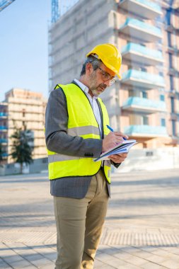 İnşaat alanı yazım notlarını denetleyen erkek mühendis