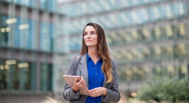 Tablet tutan iş kadını dışarıda ofis arıyor.