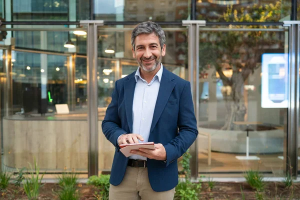 Modern ofis ortamında gülümseyen ve tablet kullanan iş adamı