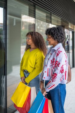 Renkli çantalar taşıyan iki kadın.