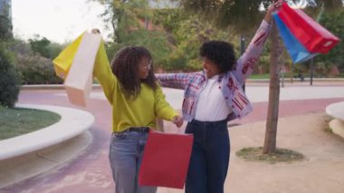Mutlu Afrikalı Amerikalı arkadaşlar alışveriş torbalarıyla yürüyorlar.