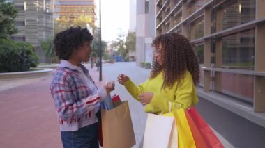 Alışverişlerini dışarıda paylaşan iki mutlu arkadaş.