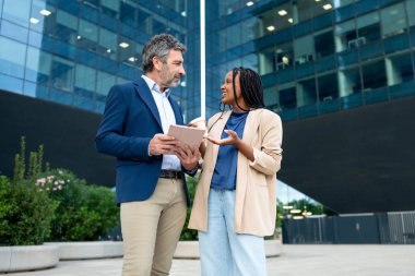 İş arkadaşları açık havada tablet kullanarak proje fikirlerini tartışıyor