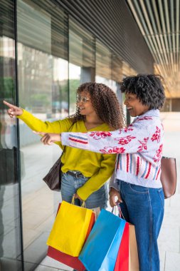 Mağaza vitrinine bakan arkadaşlar şehir vitrinlerini geziyor