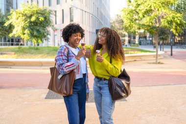İki neşeli Afrikalı Amerikalı arkadaş dondurma yiyor.