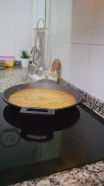 Ev yapımı paella hazırlayan birinin yakın plan fotoğrafı. Bir mutfaktaki modern bir indüksiyon çadırı üzerinde.