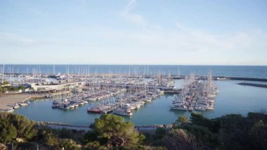 Katalonya 'da demirlemiş yelkenli ve yatlarla dolu Port Ginesta marinasının güneşli hava manzarası