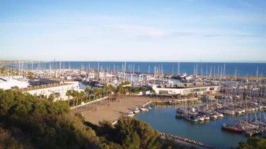 Katalonya 'da demirlemiş yelkenli ve yatlarla dolu Port Ginesta marinasının güneşli hava manzarası