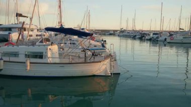 Gün batımında huzurlu bir marinada demirlemiş tekneler ve yatlar.