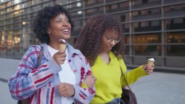 Neşeli siyah kadın arkadaşlar şehirde dondurma yerken eğleniyorlar.
