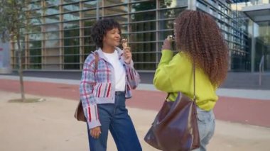 Afrikalı Amerikalı arkadaşlar dondurma yiyor ve dışarıda beşlik çakıyorlar.