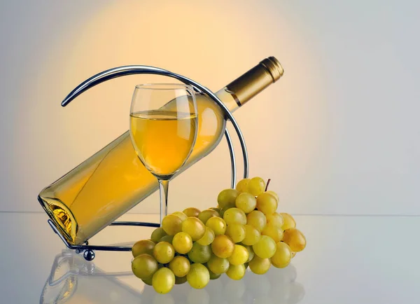Glass with wine, bottle of wine, brush of grapes on color background with copy space for your text.