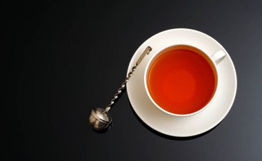 Koyu arkaplanda çay demlemek için beyaz seramik çay fincanı ve süzgeç üst görünümü ve metin alanınız için kopya alanı .