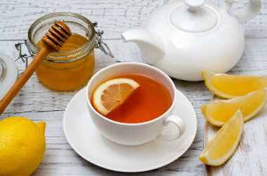 Beyaz ahşap arka planda limonlu ve ballı sağlıklı çay. Yakın plan..