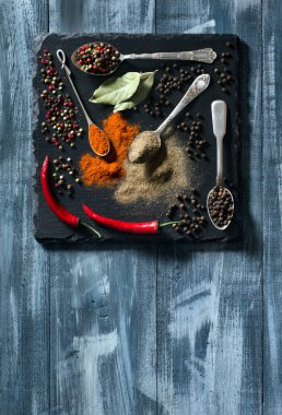 Siyah kesme tahtasındaki çeşitli baharatlar ve metin için alanı olan mavi ahşap arka plan. Üst görünüm.