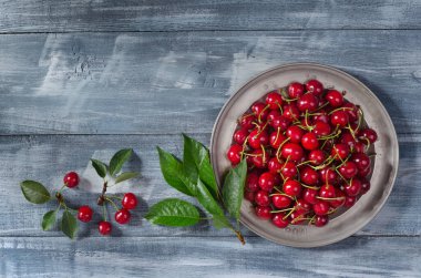 Ahşap zemin üzerinde olgun kirazlar ve metin için fotokopi alanı olan klasik metal plaka. Üst Manzara. Düz yatıyordu.