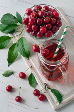 Cam mason kavanozunda kiraz suyu ve beyaz tuğla duvarda kiraz meyvesi. Yakın plan. Üst görünüm.