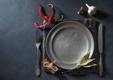 Eski çatal bıçak takımı ve çeşitli baharatlar. Siyah arka planda. Metnin için fotokopi alanı var. Üst Manzara. Düz yatıyordu.