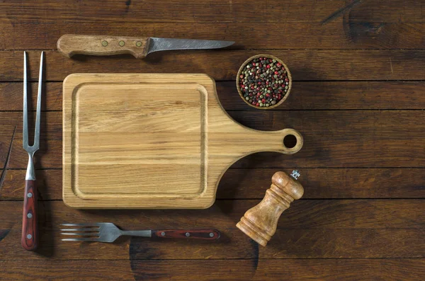 Kitchen utensils and spices for barbecue on old wood table in rustic style with copy space for your text. Top view.