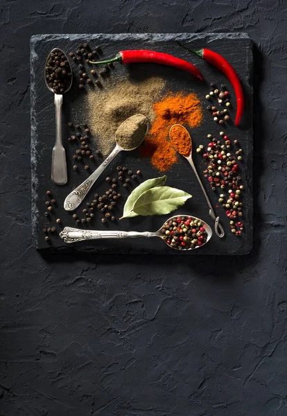Renkli çeşitli baharatların üst görüntüsü klasik metal kaşıklarda siyah desenli arka planda metnin için yer var. Yemek sanatı.